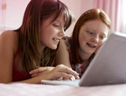 Bilde av to unge jenter sitter foran en datamaskin. Bildet illustrerer at det er vanlig å ha mange spørsmål, og o.b.®'s hjemmeside kan du finne informasjon om første menstruasjon, pubertet og annen nyttig informasjon